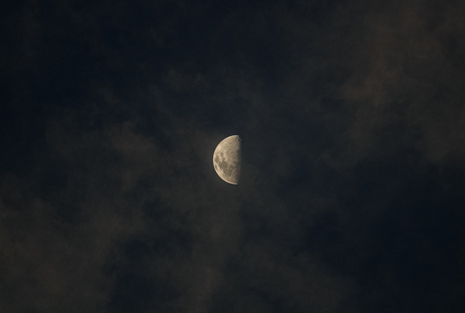 a half moon is seen through the clouds